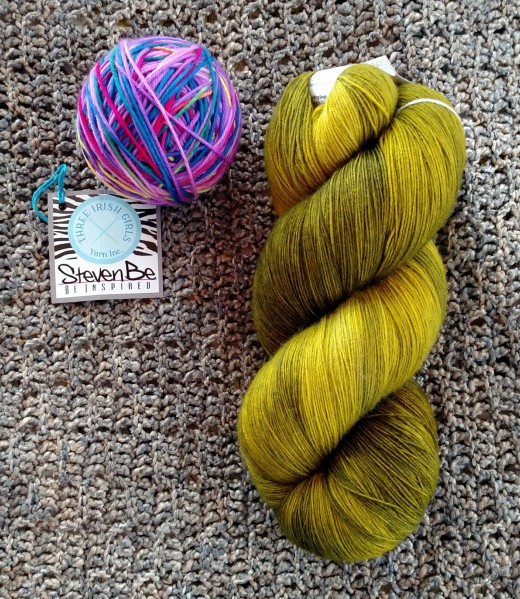 photo of rainbow yarn and a large skein of mossy green yarn